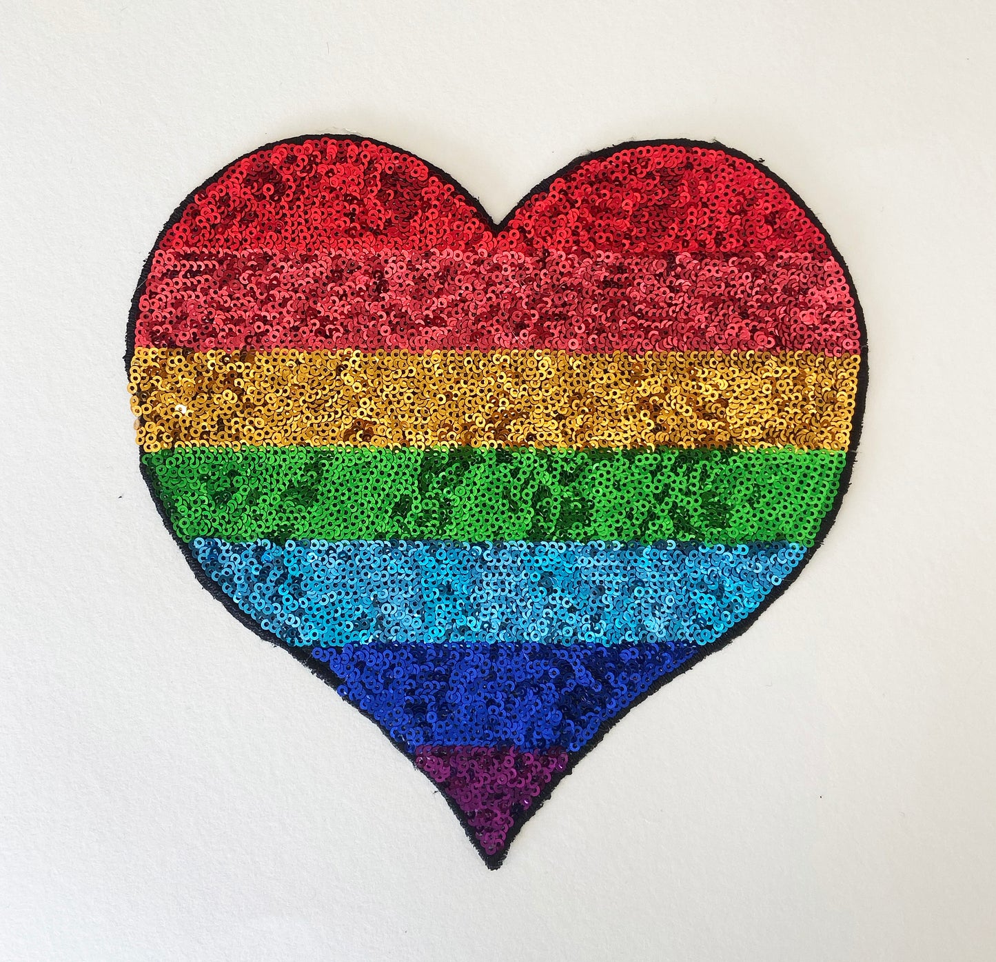 Heart-shaped patch with rainbow pattern on a white background
