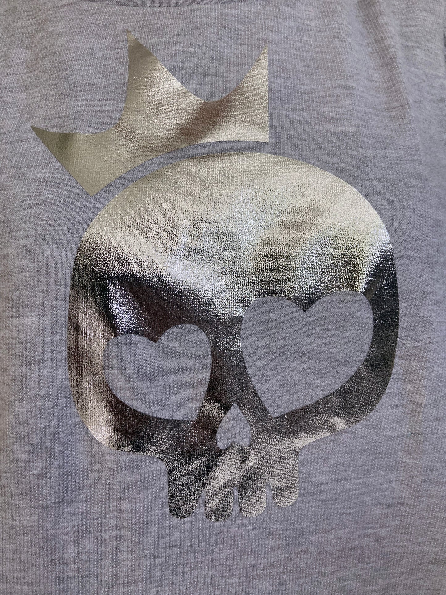 Gray sweatshirt with a metallic skull design and heart shapes on a gray background