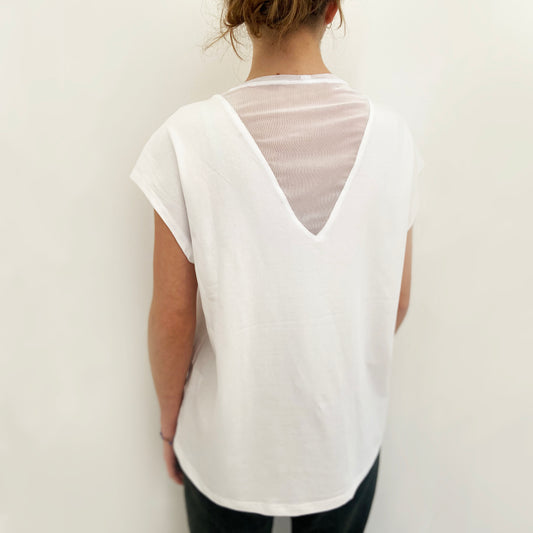 Person wearing a white sleeveless top with a V-neckline against a plain background