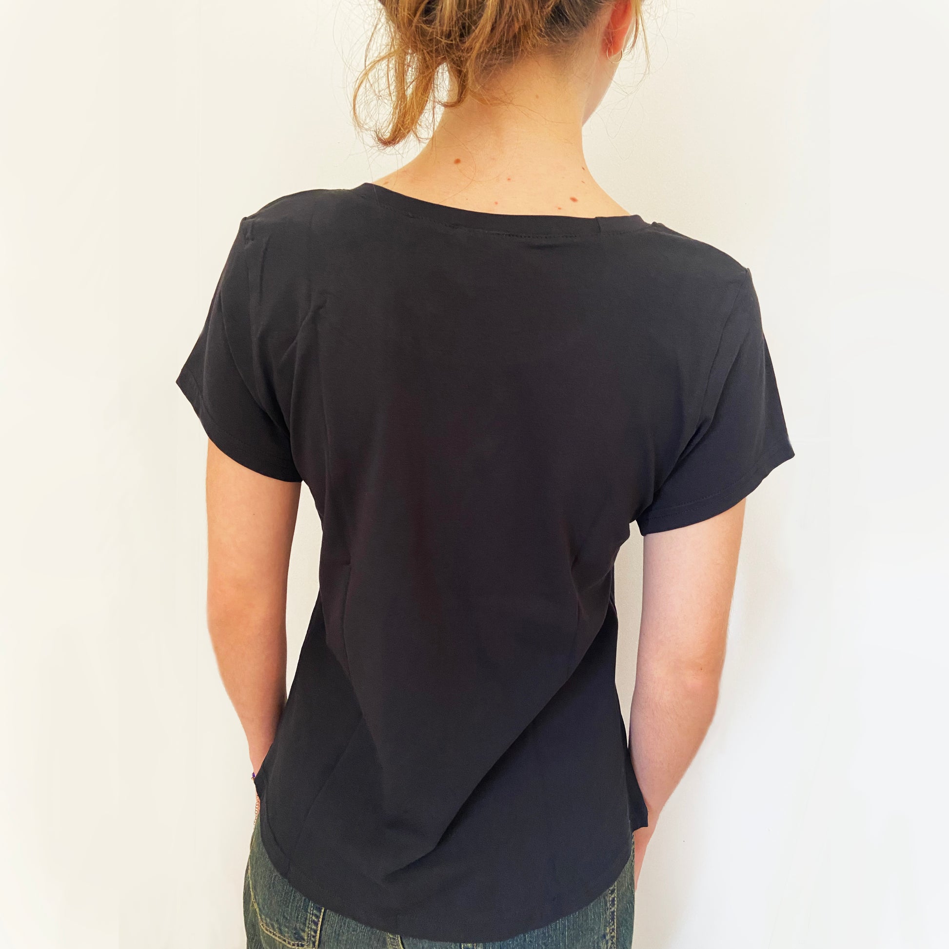 Person wearing a black t-shirt with a plain background