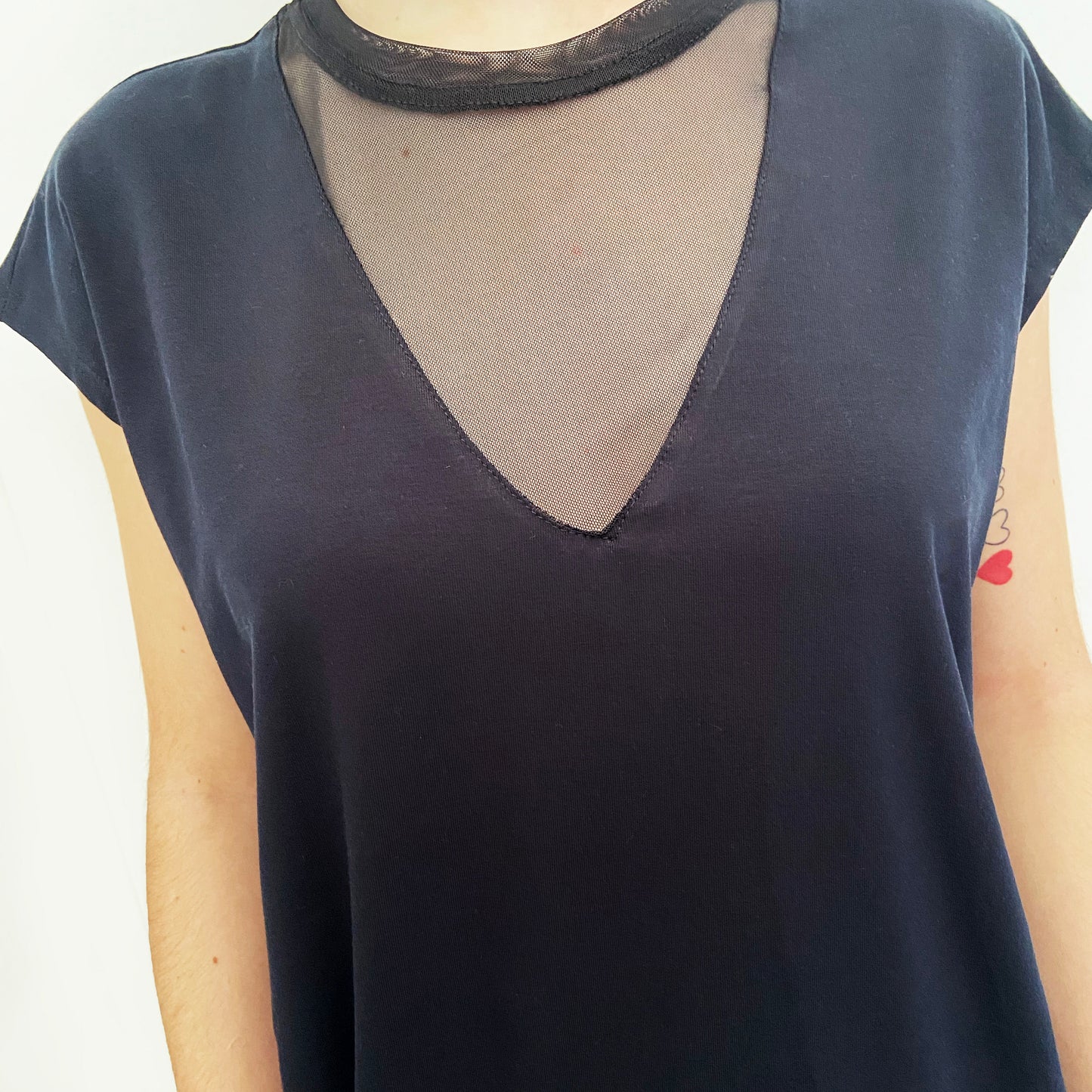 Black top with sheer mesh detail on a white background