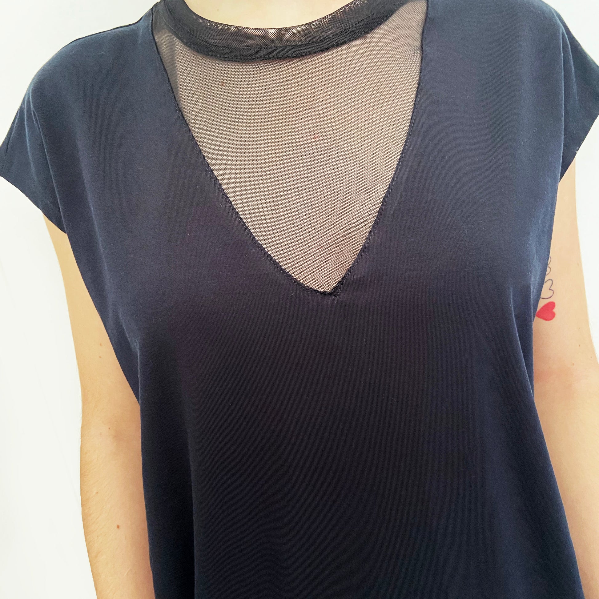 Black top with sheer mesh detail on a white background