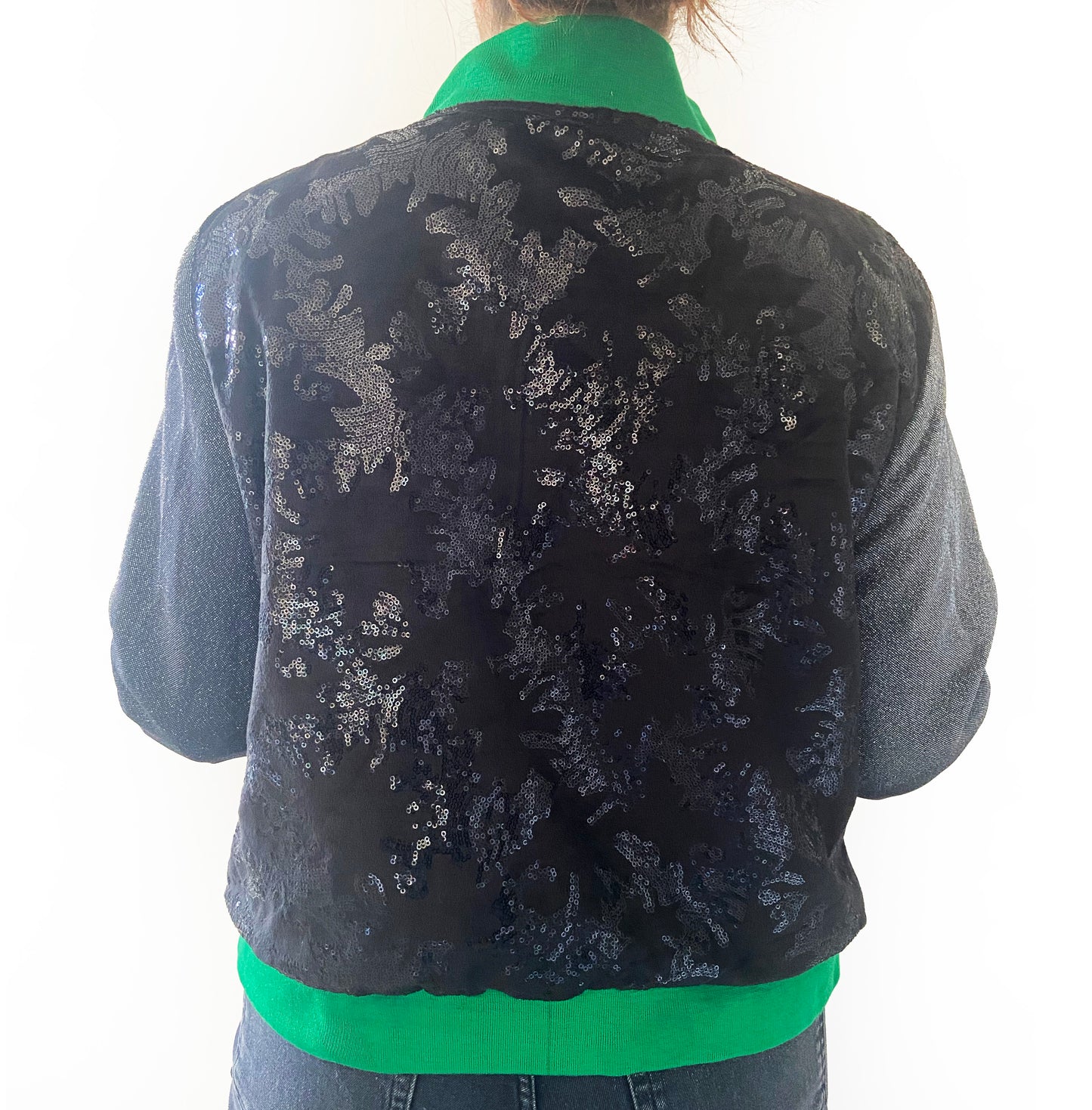 Black floral sequin patterned jacket with green trim on a white background