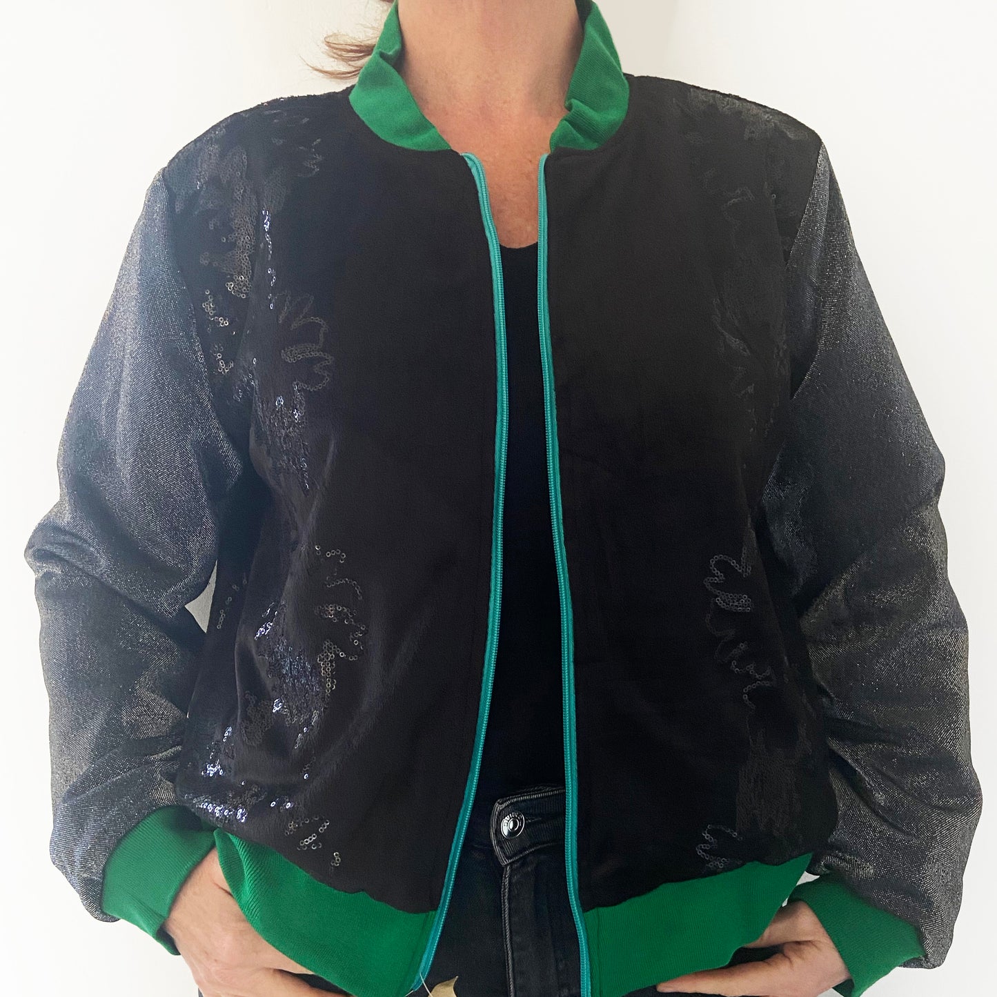 Person wearing a black jacket with green accents on a white background