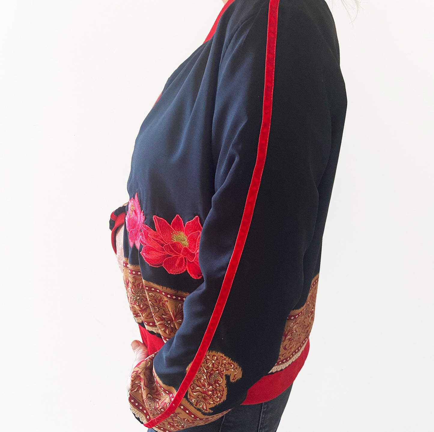Black garment with red and gold floral and paisley patterns on a white background