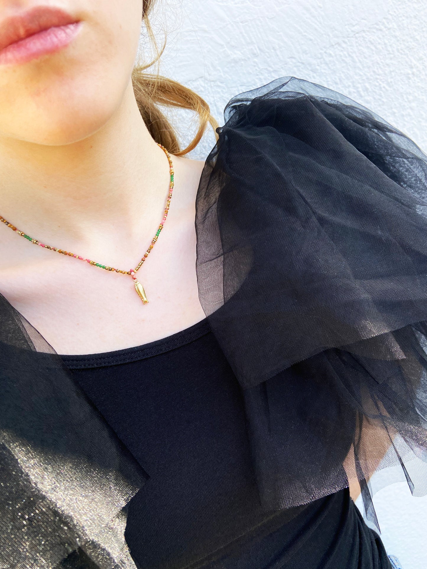 Close-up of a person wearing a black sheer top with a gold necklace.
