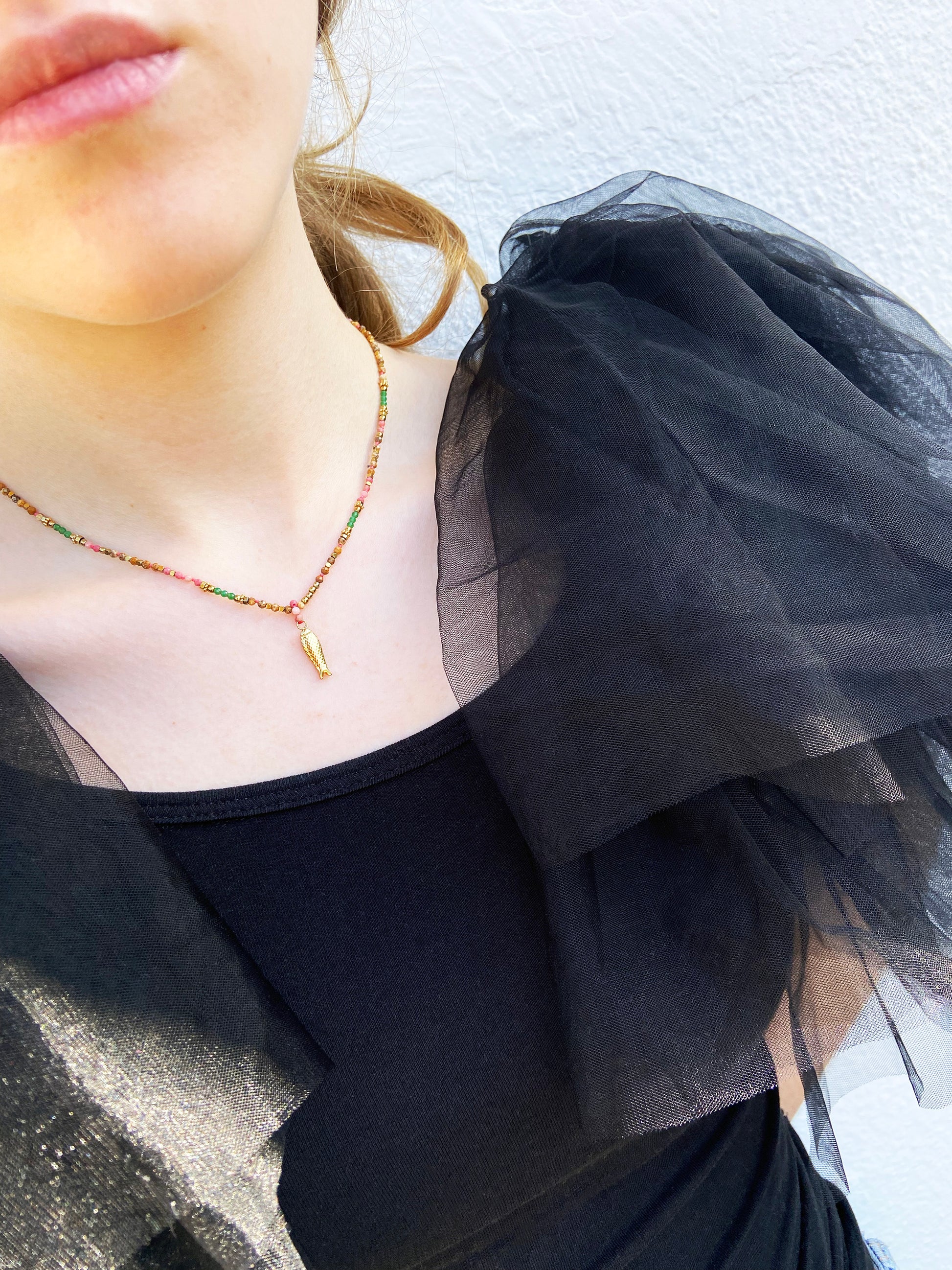 Close-up of a person wearing a black sheer top with a gold necklace.