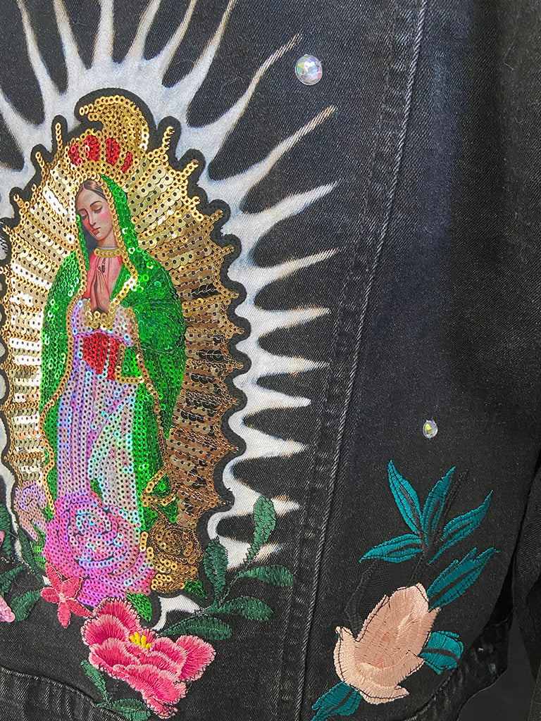 Embroidered design of a religious figure on a black background with floral elements.