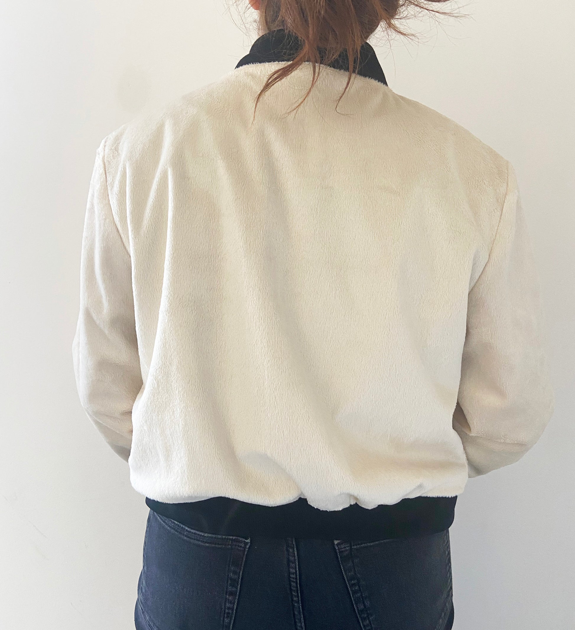 Person wearing a cream-colored jacket against a white background