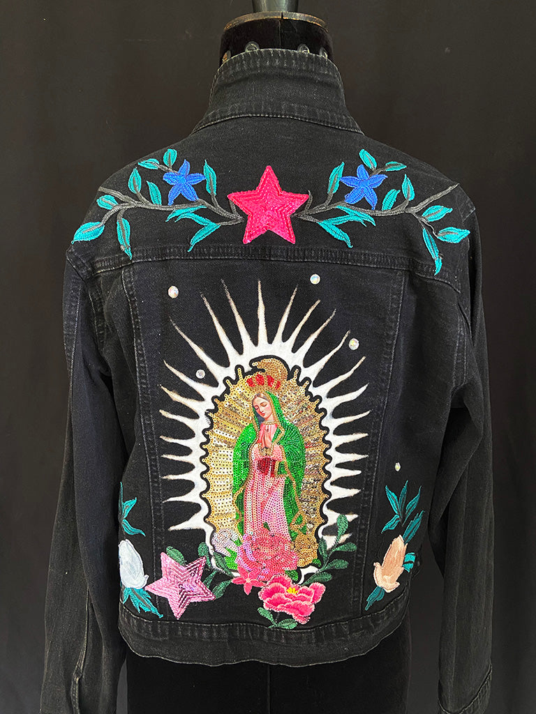 Black denim jacket with colorful embroidery on a dark background