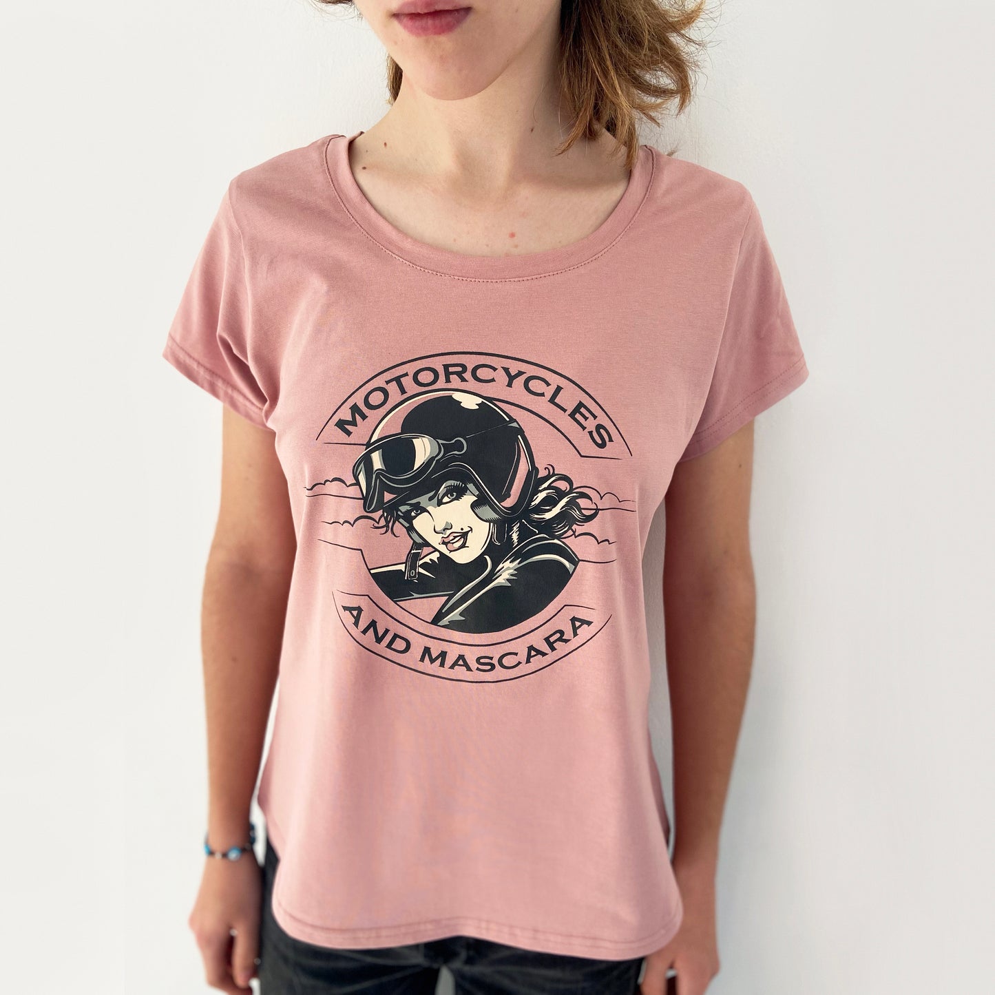 Pink t-shirt with 'Motorcycles and Mascara' graphic worn by a person on a white background
