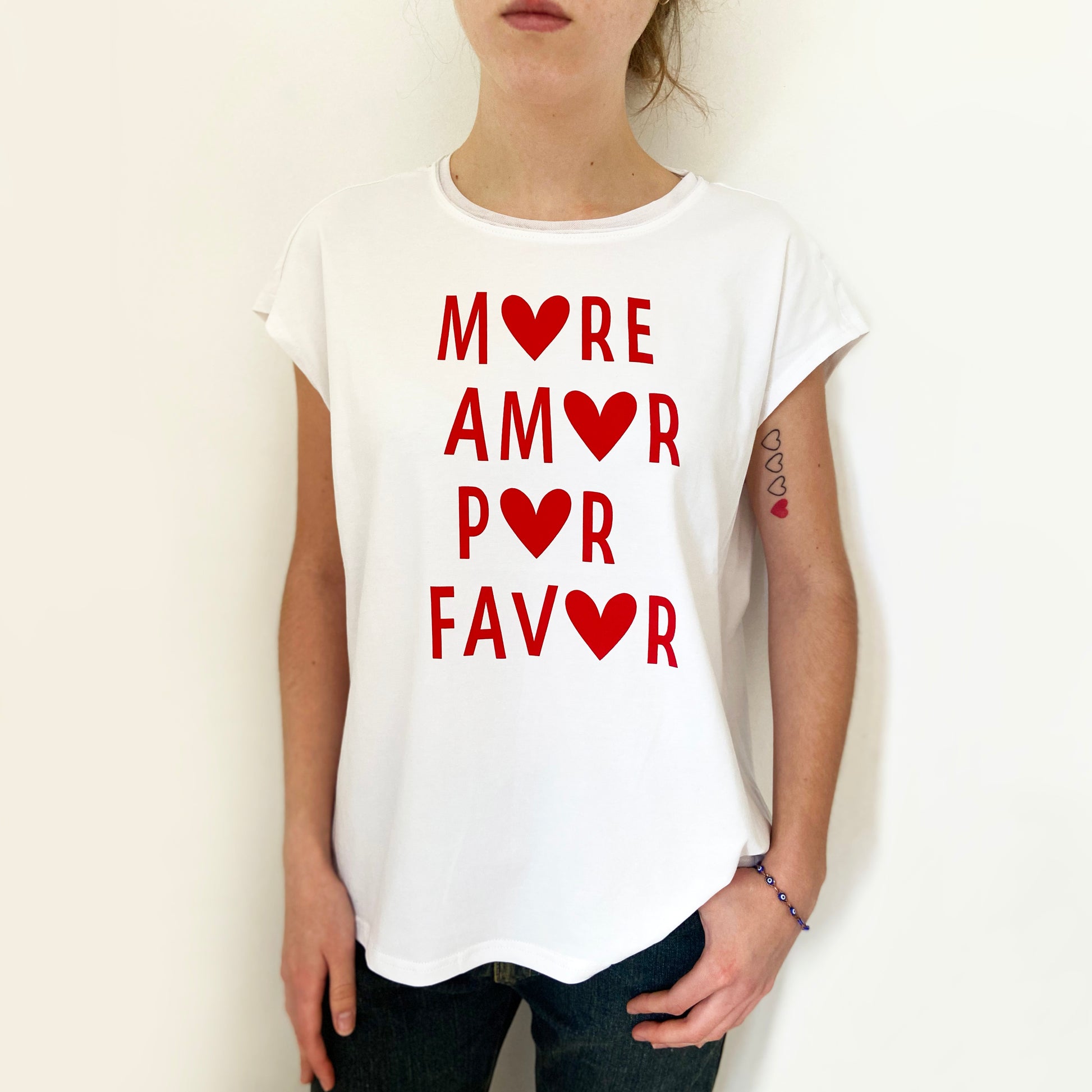 Person wearing a white t-shirt with red text and heart symbols on a plain background