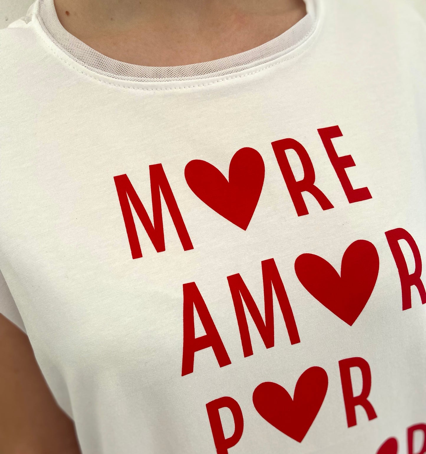 White t-shirt with red text and heart symbols on a plain background