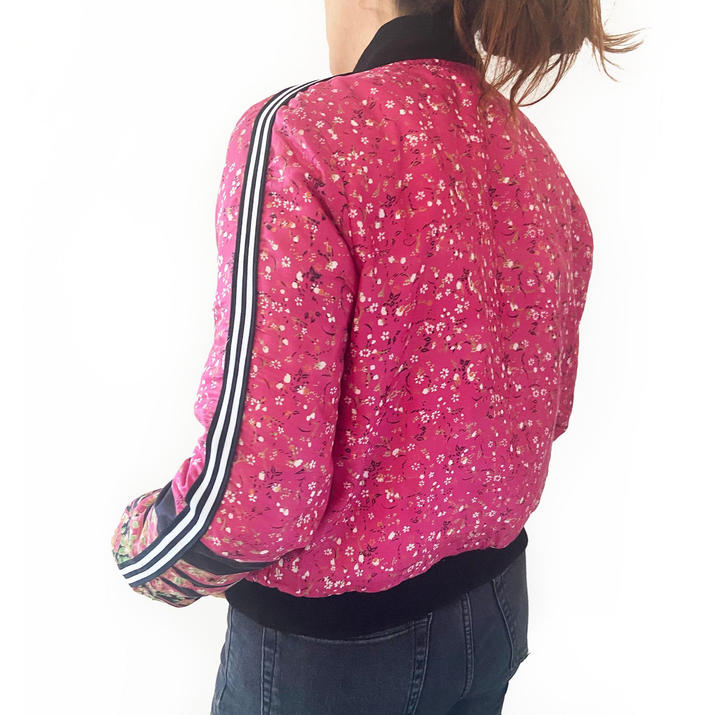 Person wearing a pink floral jacket with white stripes on the sleeves against a white background