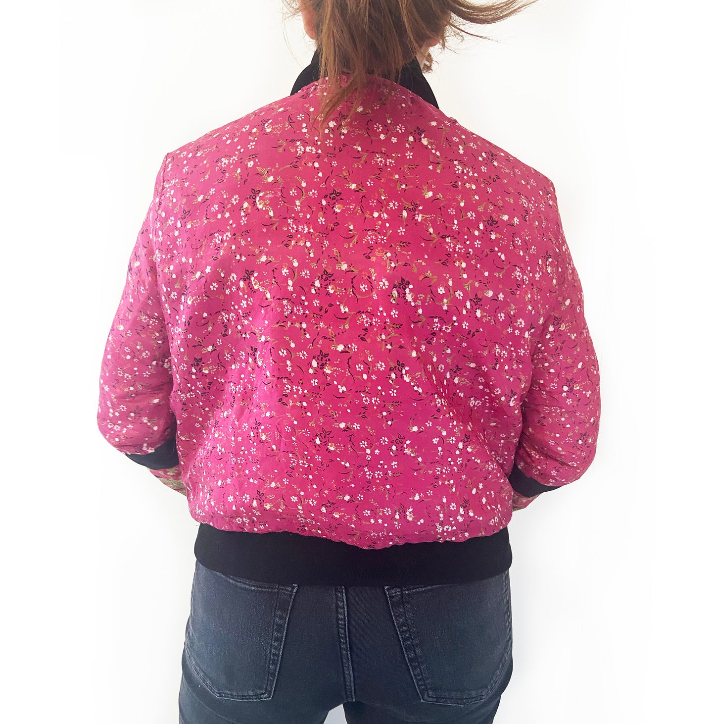 Person wearing a pink floral jacket on a white background
