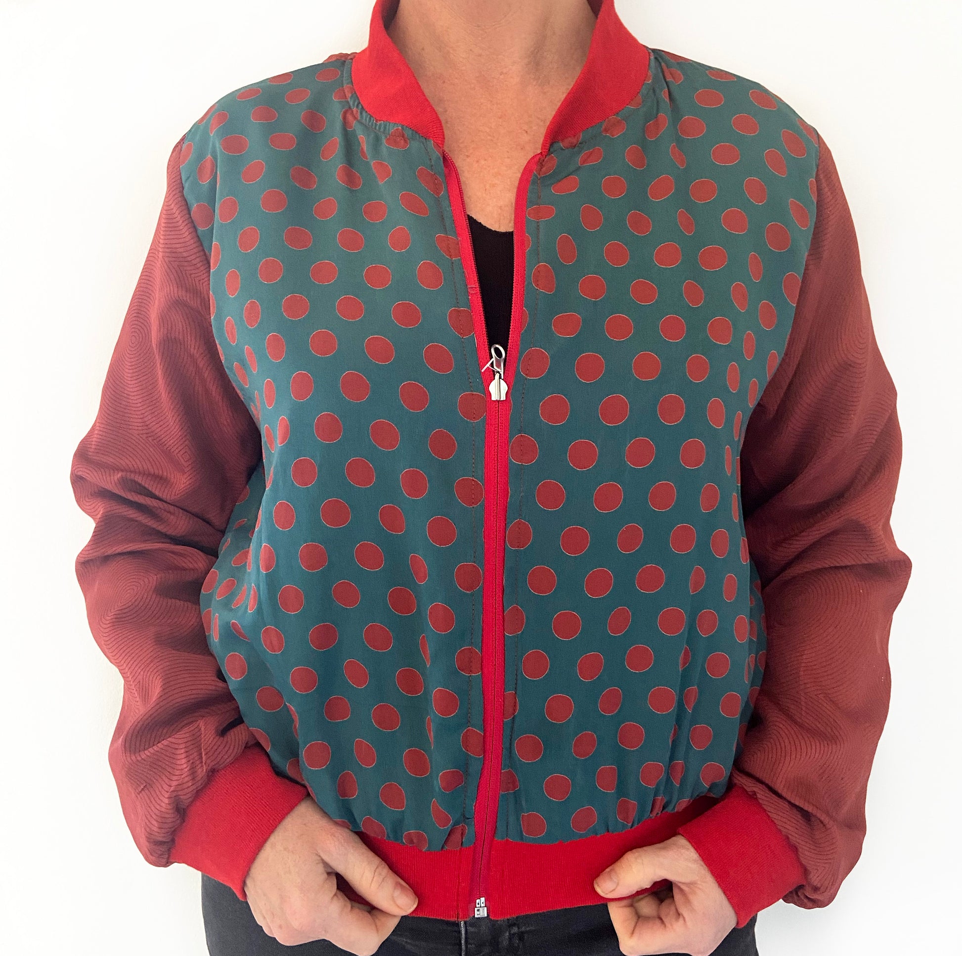 Person wearing a red and green polka dot jacket with a white background