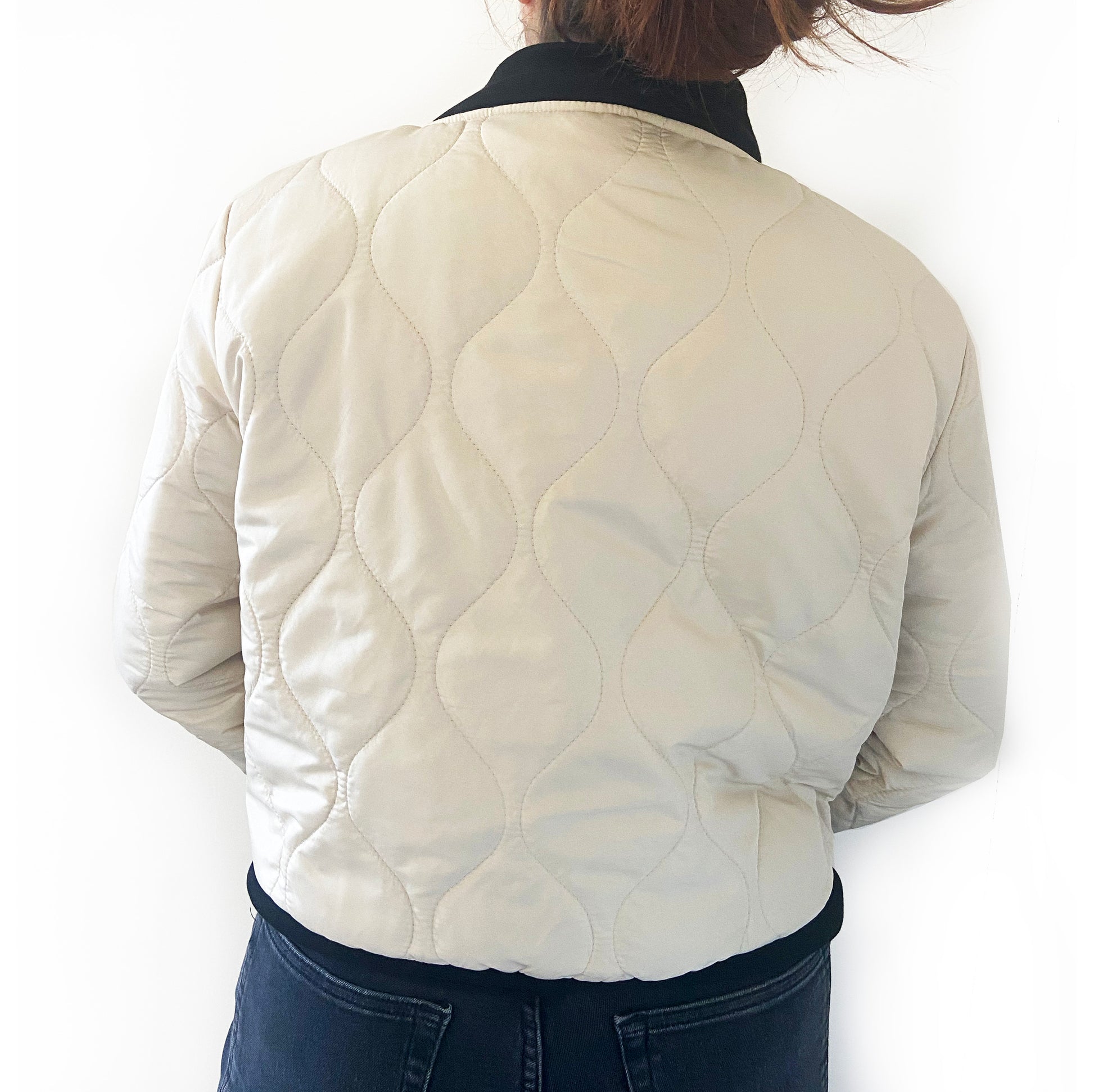 Person wearing a quilted cream jacket on a white background