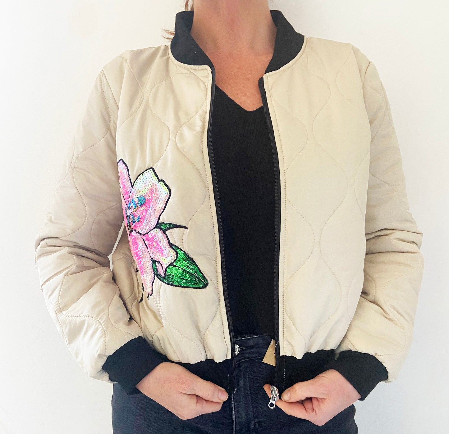 Cream bomber jacket with a colourful flower design on a white background