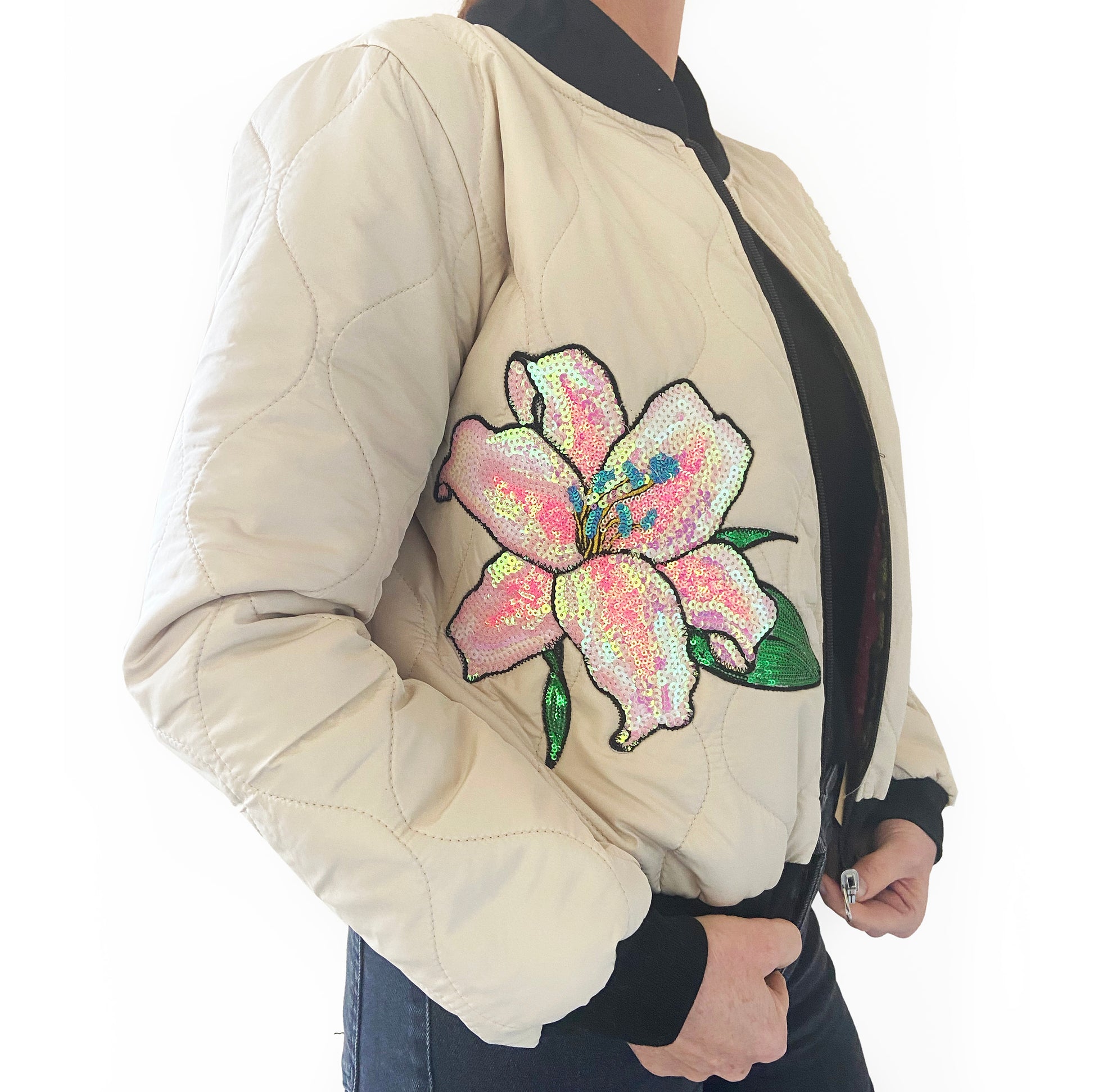 Cream bomber jacket with a colourful floral sequin design on a white background