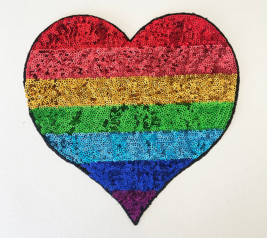 Heart-shaped patch with rainbow sequin pattern on a white background