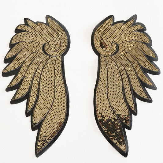 Pair of gold and black wing-shaped  sequin patches on a white background