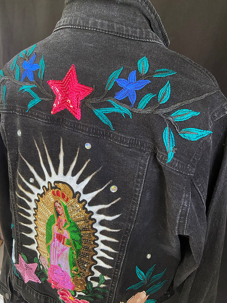 Black denim jacket with colorful embroidery and a Virgin Mary design on the back.
