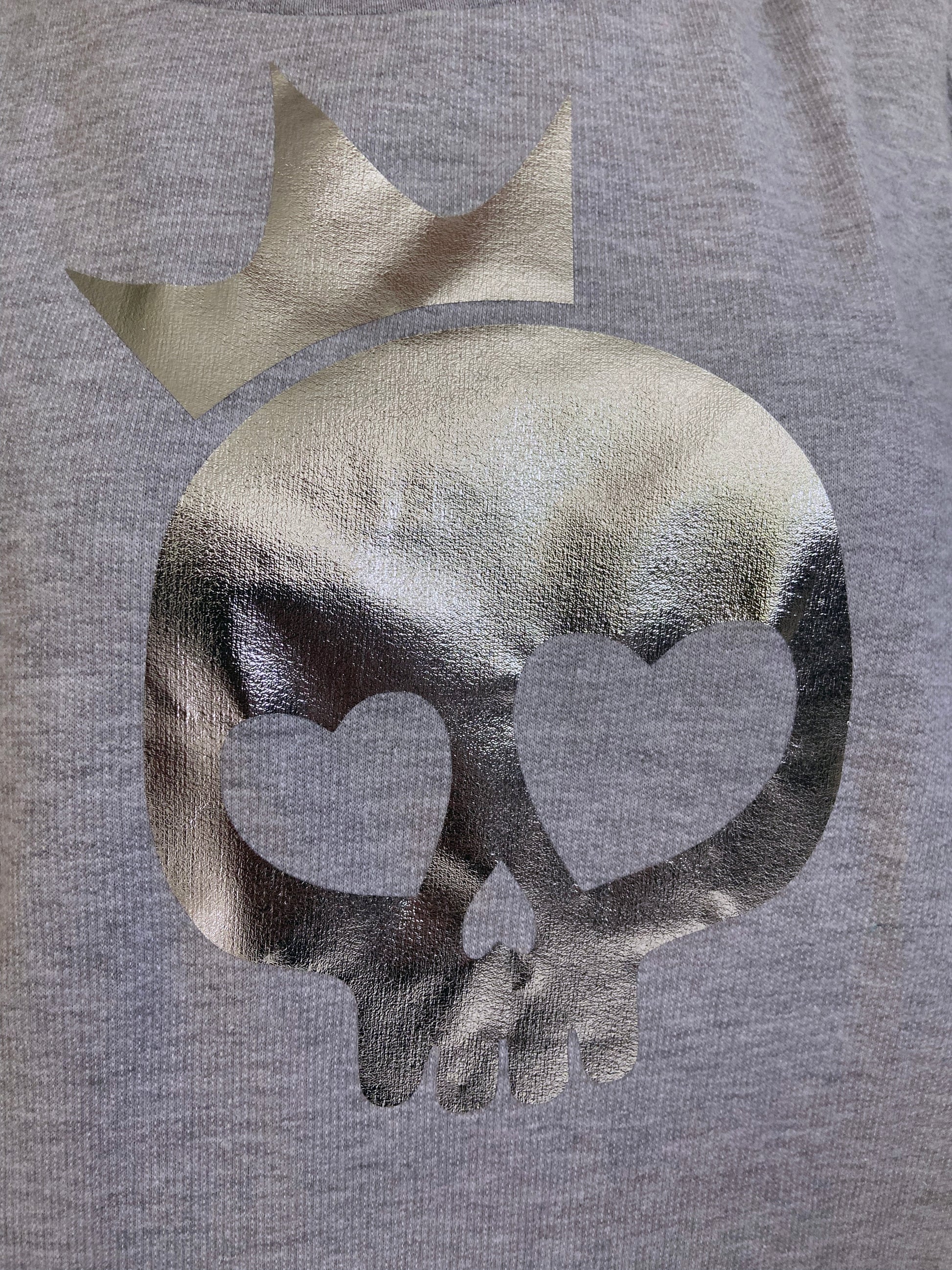 Gray sweatshirt with a metallic skull design and heart shapes on a gray background