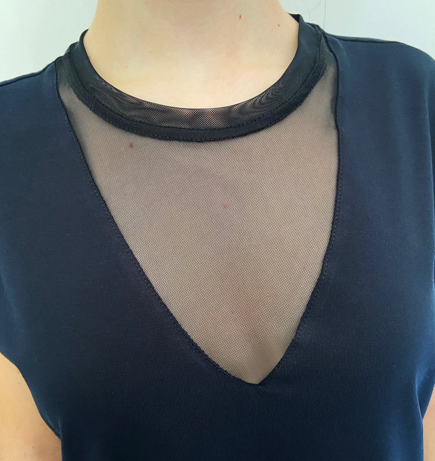 Black top with mesh detail on a plain background