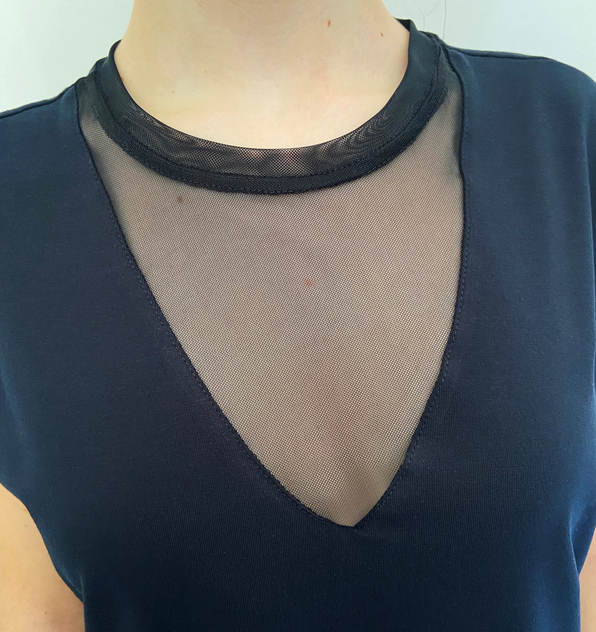 Black top with mesh detail on a plain background
