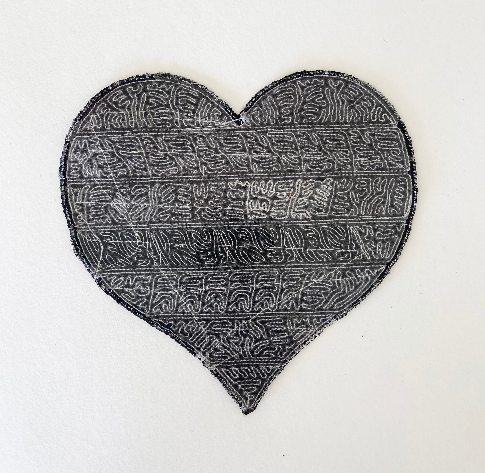 back of heart-shaped motif with a textured pattern on a white background