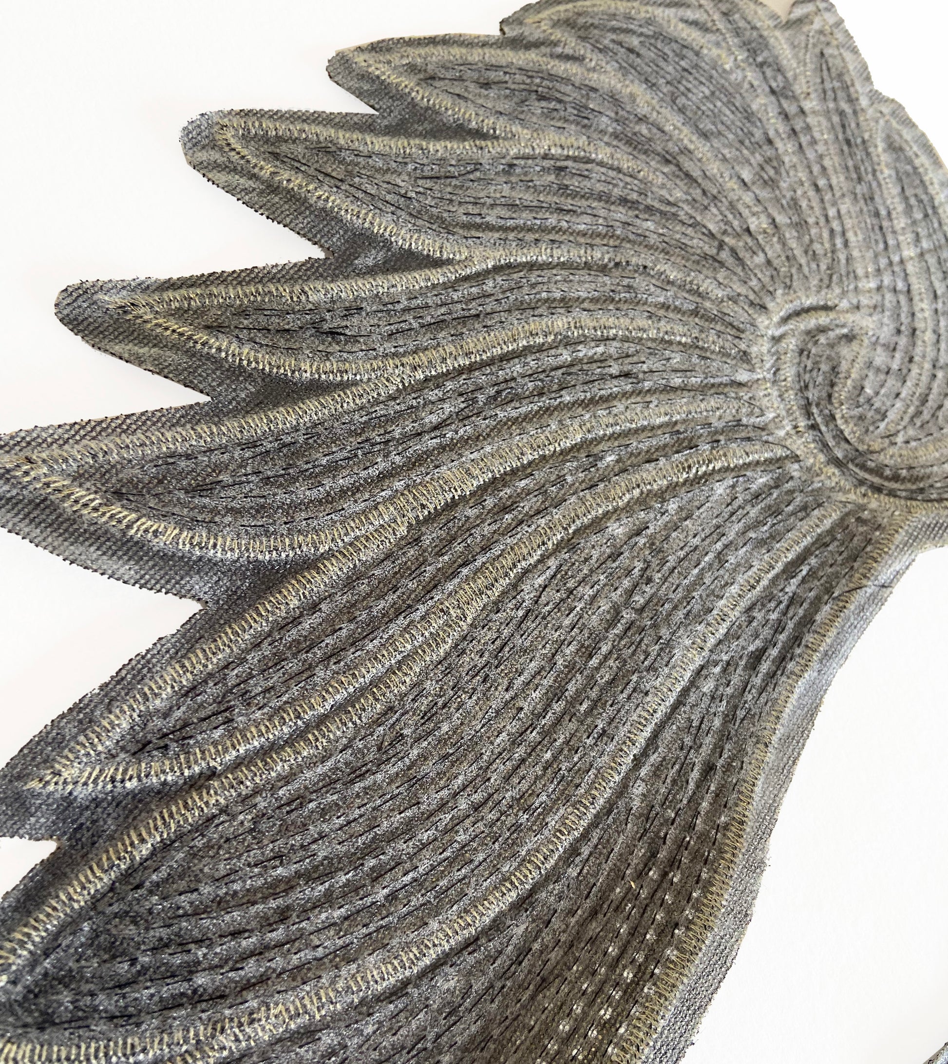 Close-up of a decorative metallic leaf design on a white background