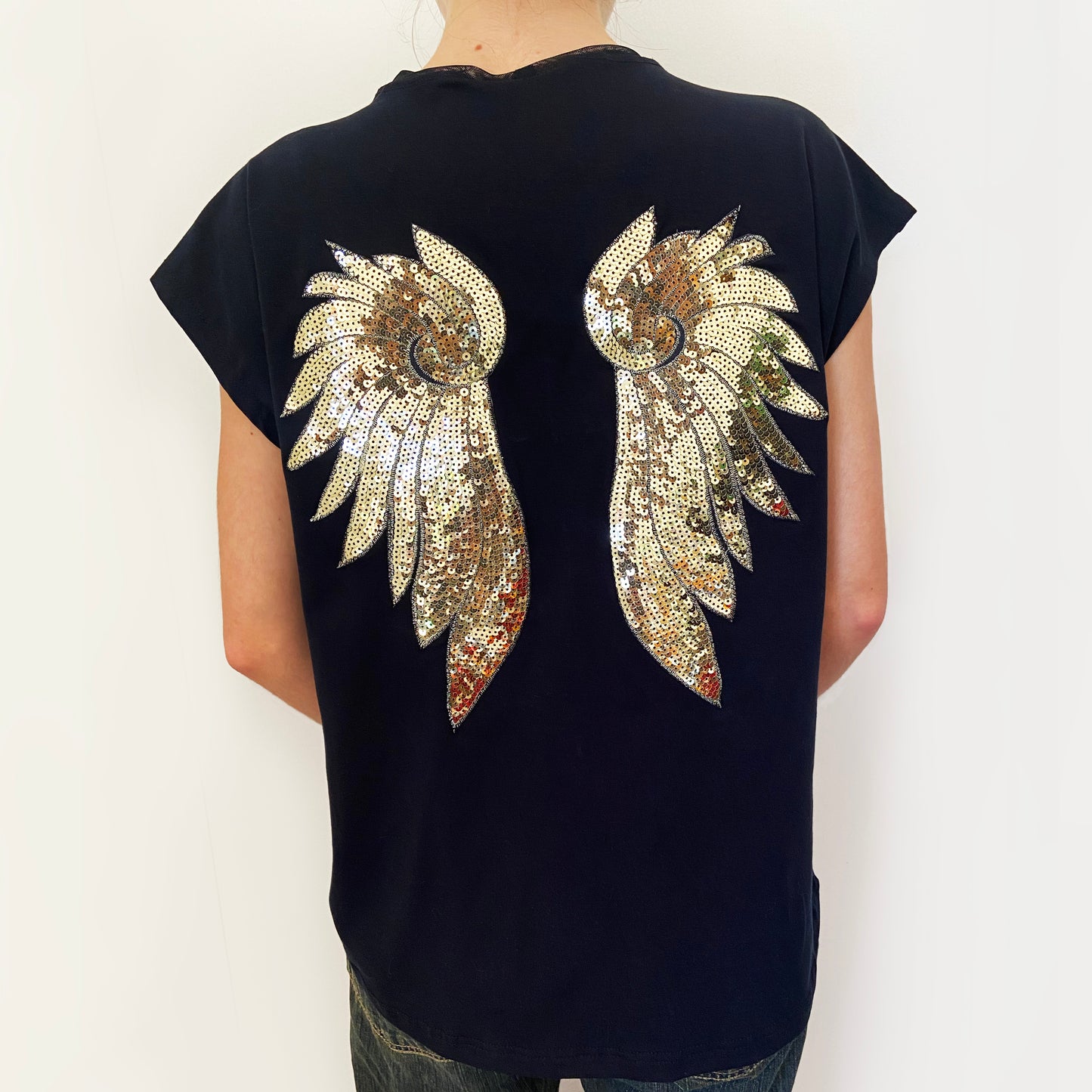 Black t-shirt with gold sequin wings on the back against a white background