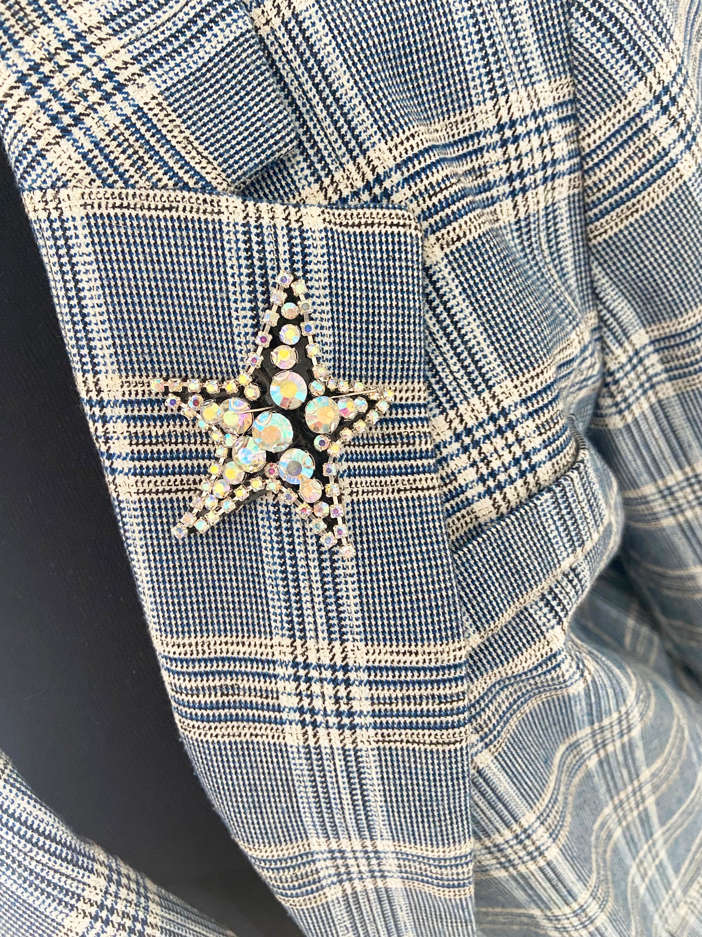 Close-up of a blue and white checkered fabric with a star-shaped brooch.