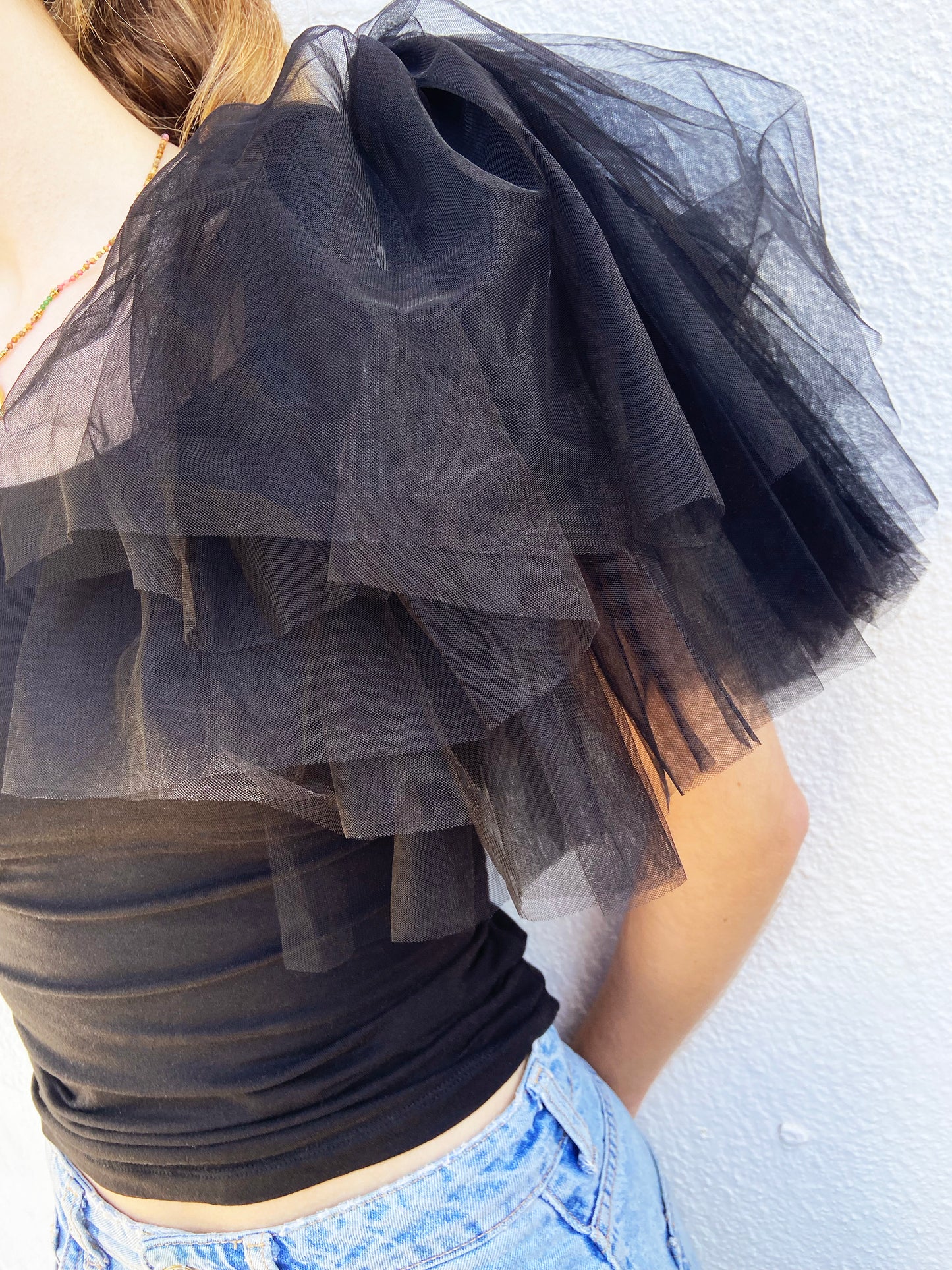 Black layered tulle fabric draped over a person against a white background