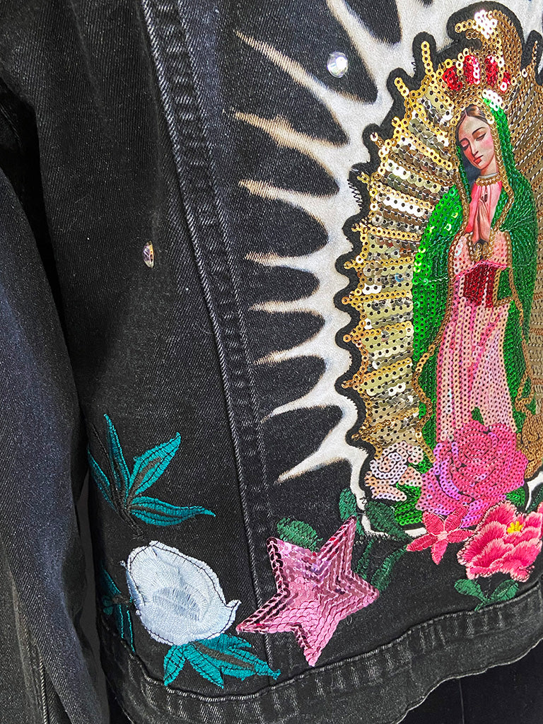 Black jacket with embroidered design of a religious figure, flowers, and stars.
