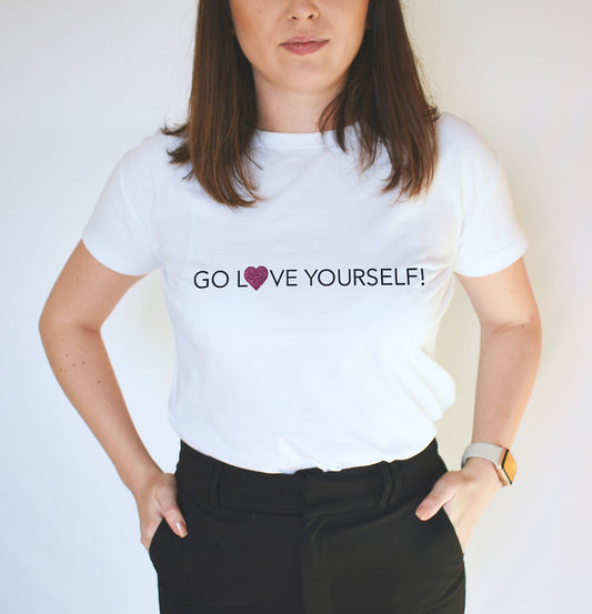 A person wearing a white t-shirt with the text 'GO LOVE YOURSELF!' and a glitter vinyl heart graphic on the front.