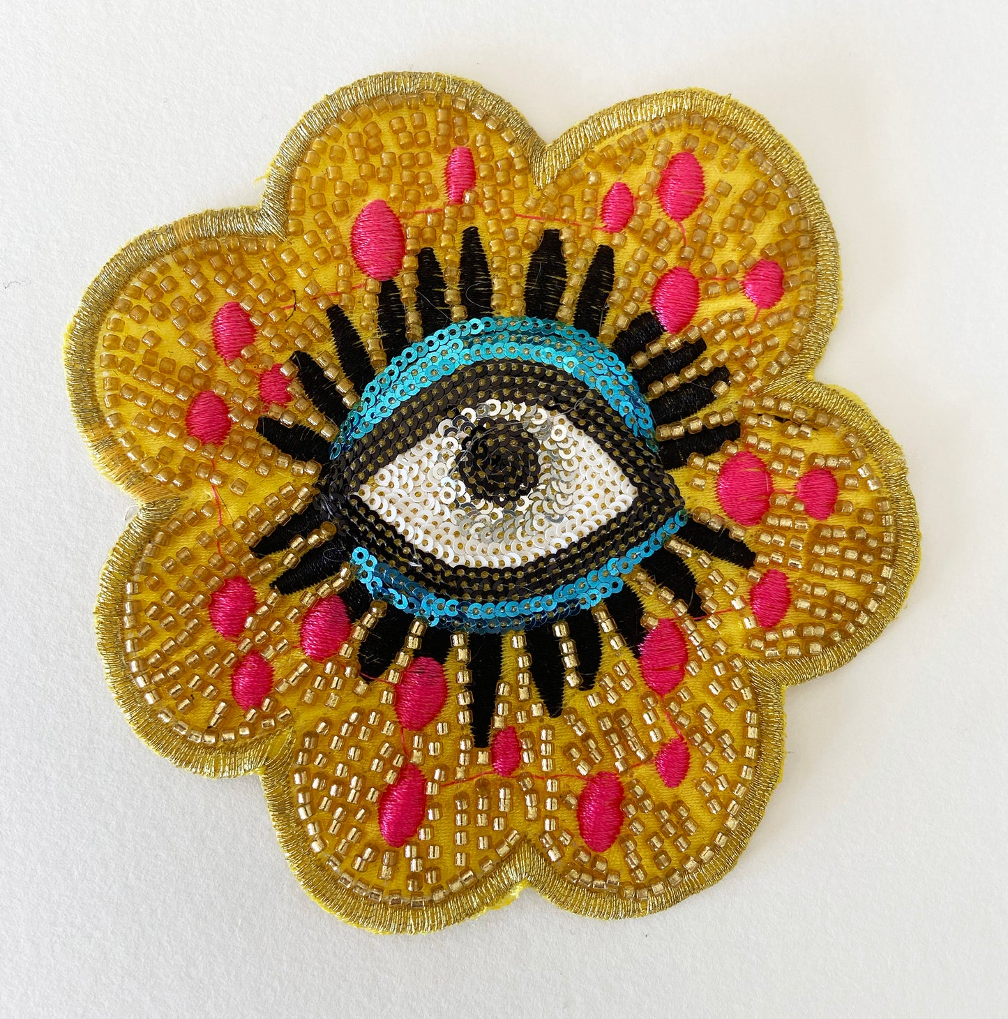 Decorative patch with an eye design on a yellow flower-like background