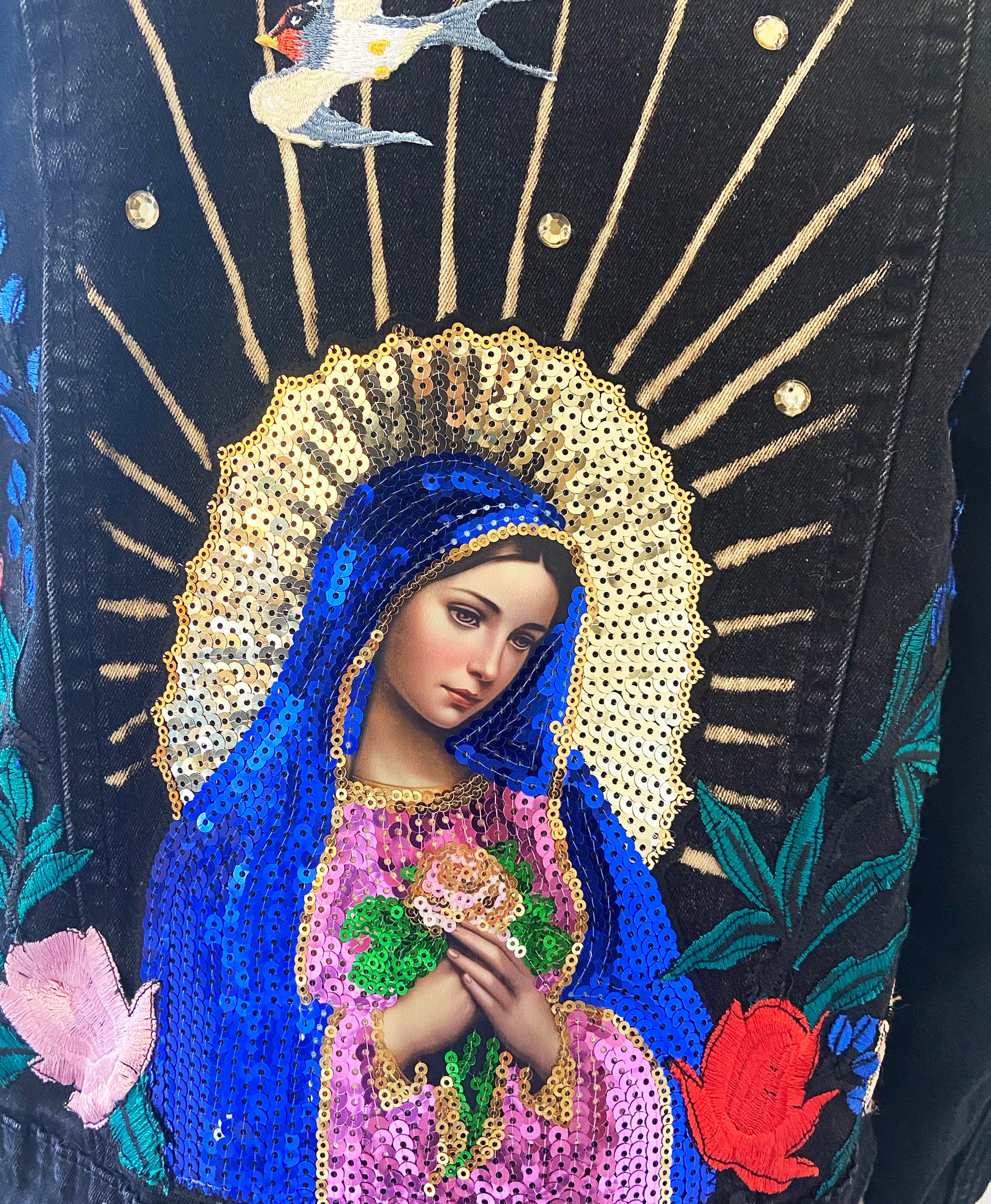 Decorative item with a religious icon, blue and gold robe, and floral elements on a dark background.
