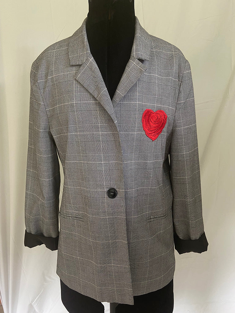 Gray checkered blazer with a red heart patch on a mannequin against a white background