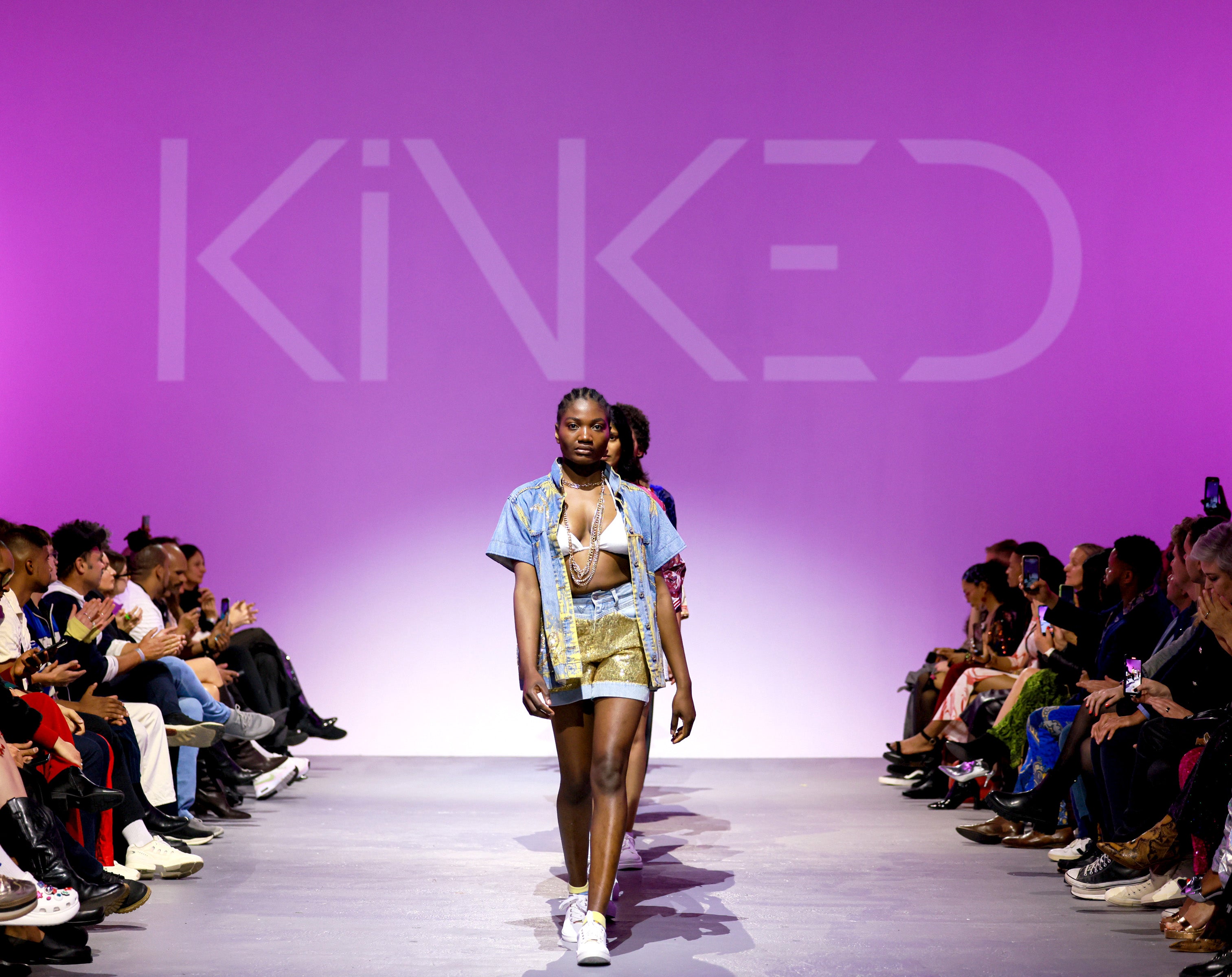 Model walking on a runway with 'Kinked' branding in the background