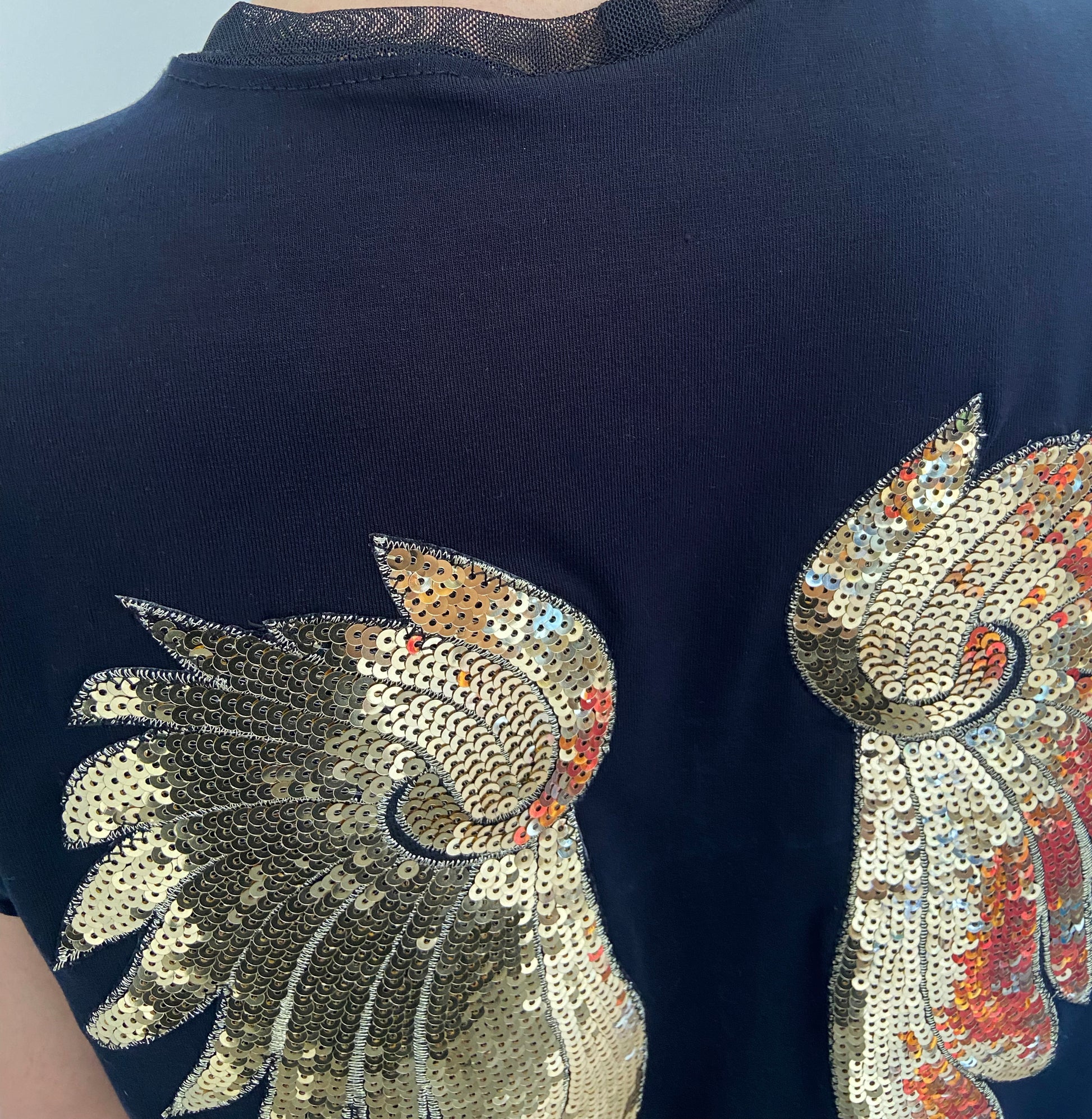 black shirt with sequin wings designs on a plain background