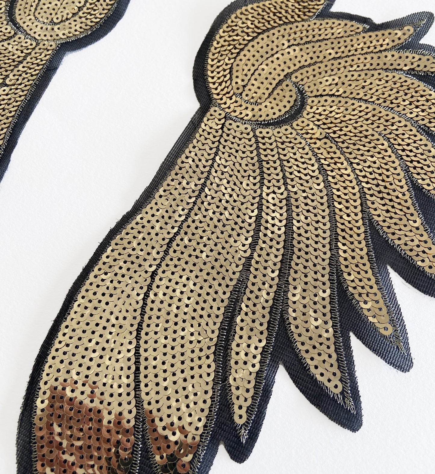 Gold sequin patch with black outline on a white background