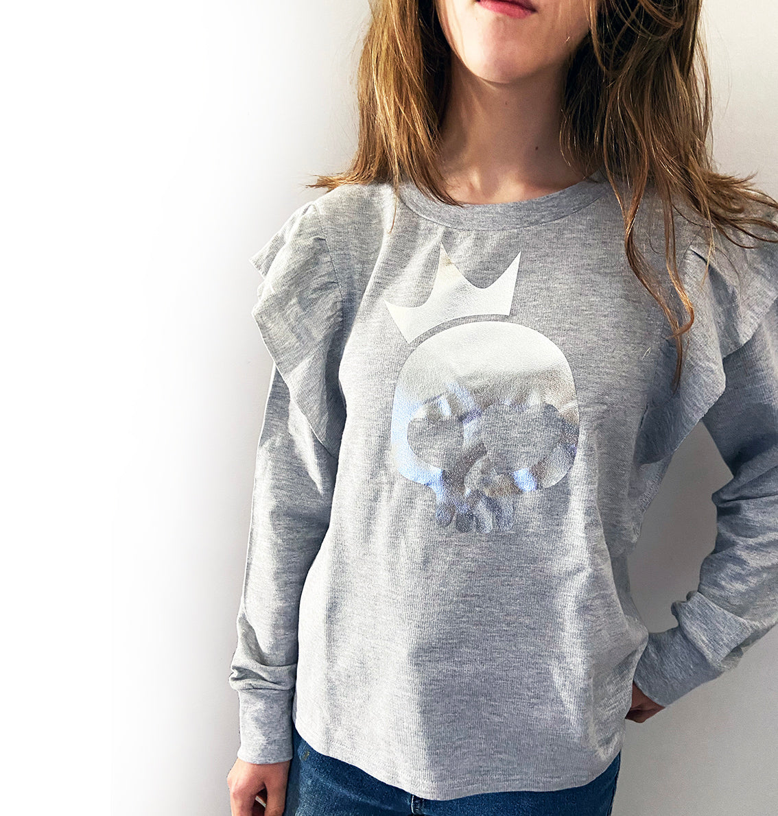 a person wearing a light grey shirt with silver foil skull print.