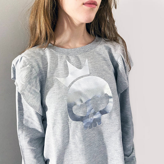 a person wearing a light grey shirt with silver foil skull print.