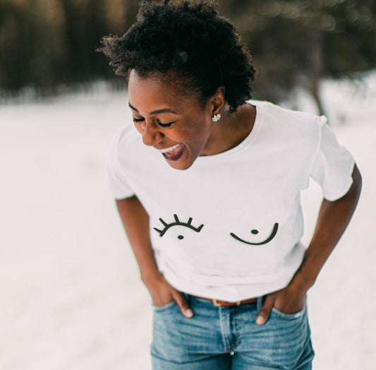a woman laughing in a white t-shirt with a black graphic print on