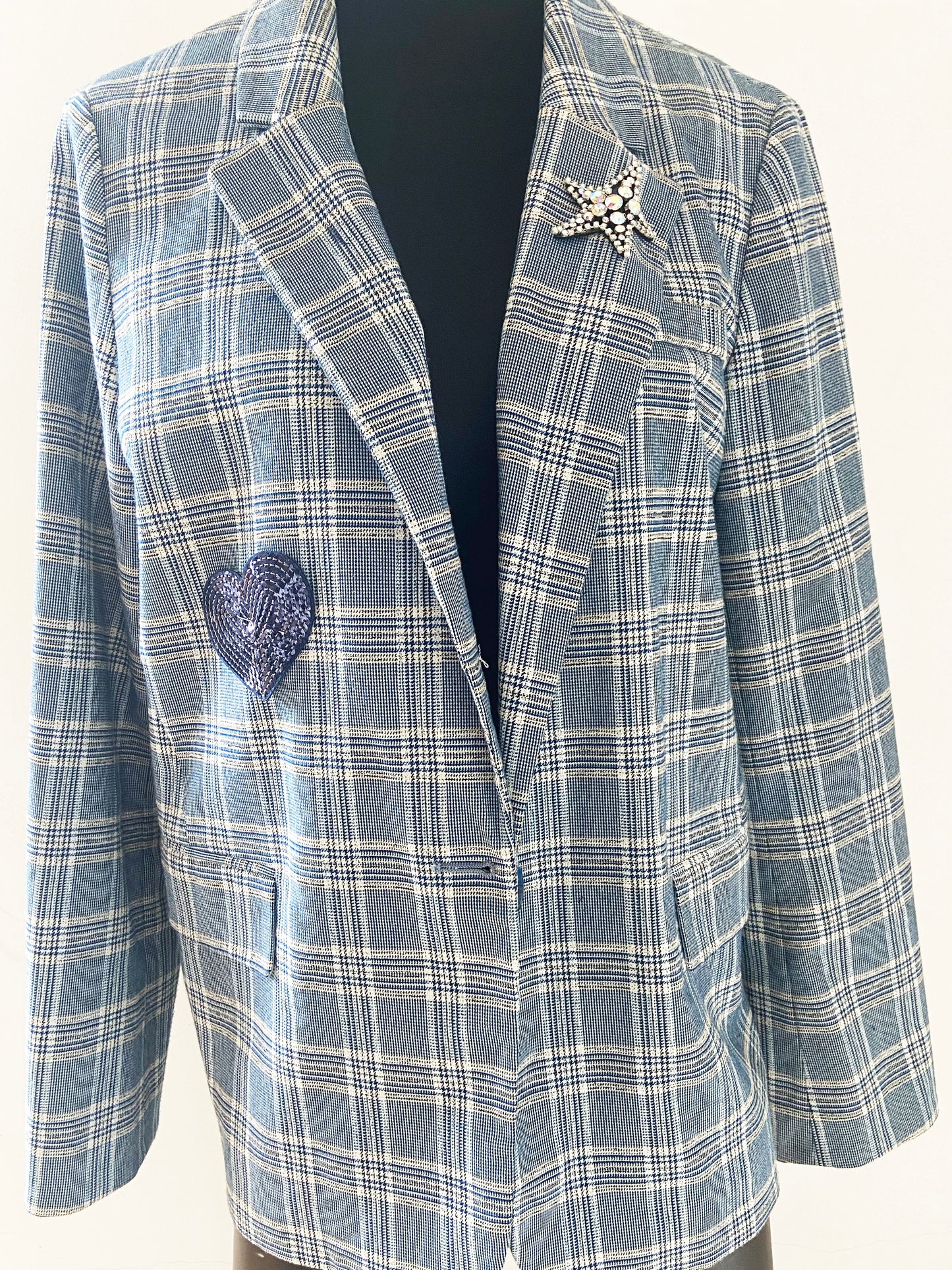 Blue plaid blazer with decorative heart and star brooches on a white background