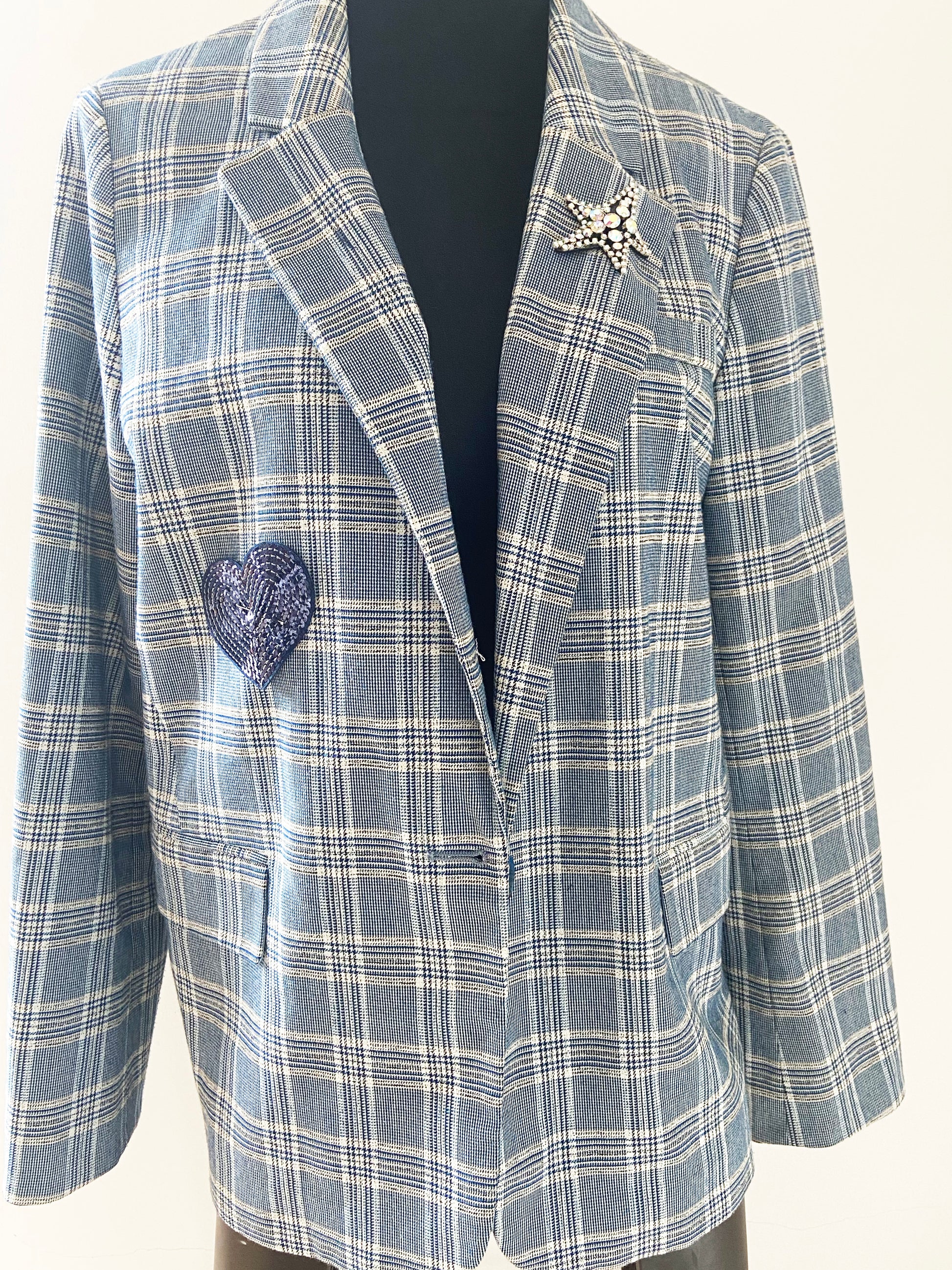 Plaid blazer with decorative brooches on a white background